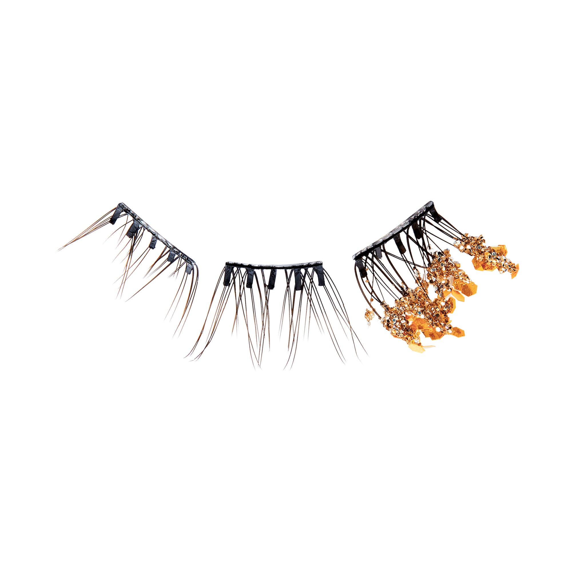 The image features a set of three pairs of false eyelashes. The lashes vary in design and texture. The first two pairs have a dramatic, spiky appearance with long, black strands, while the third pair is adorned with golden embellishments, giving it a more ornate and glamorous look. The overall presentation highlights the creativity and artistry involved in eyelash design, suitable for bold makeup styles.