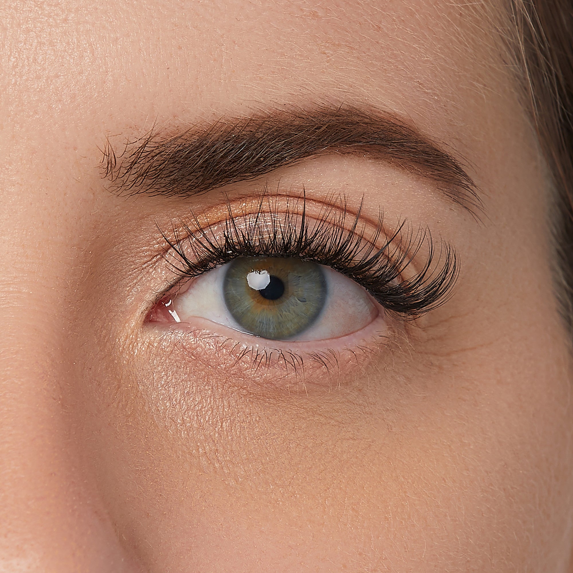 The image features a close-up of a human eye, showcasing a striking combination of colors in the iris, which appears to have shades of green and hints of brown. The eyelashes are long and well-defined, enhancing the eye&