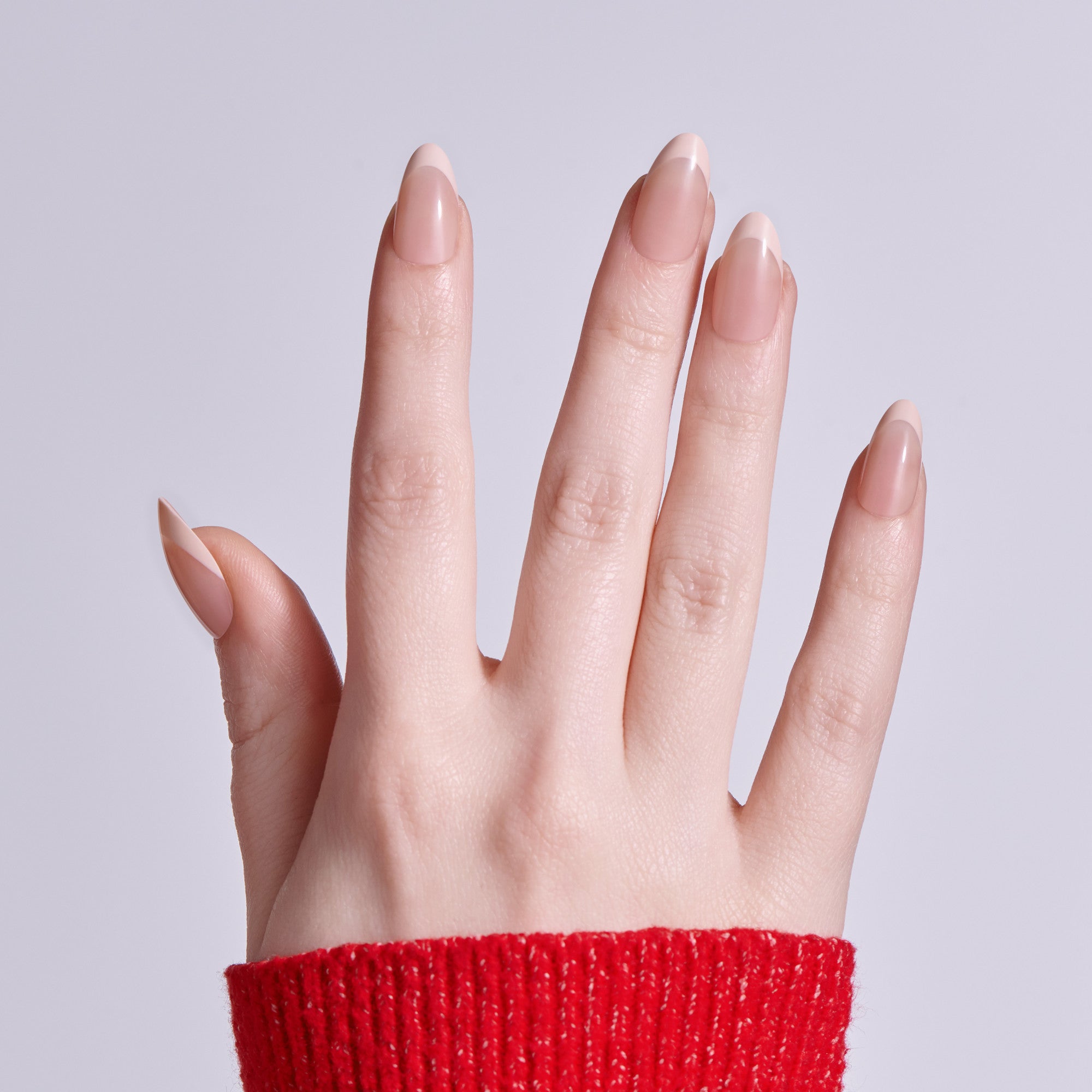 Hand with almond-shaped nails and white tips wearing red sweater cuff