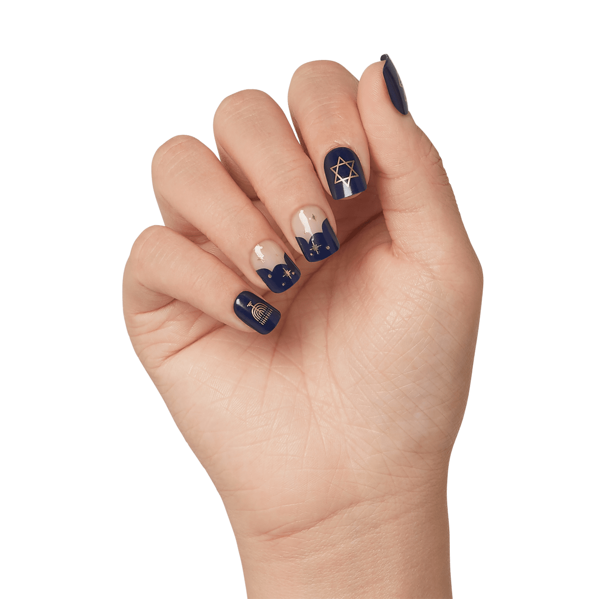 Hand with navy blue and nude press-on nails featuring gold Hanukkah designs including a menorah, Star of David, and decorative stars.