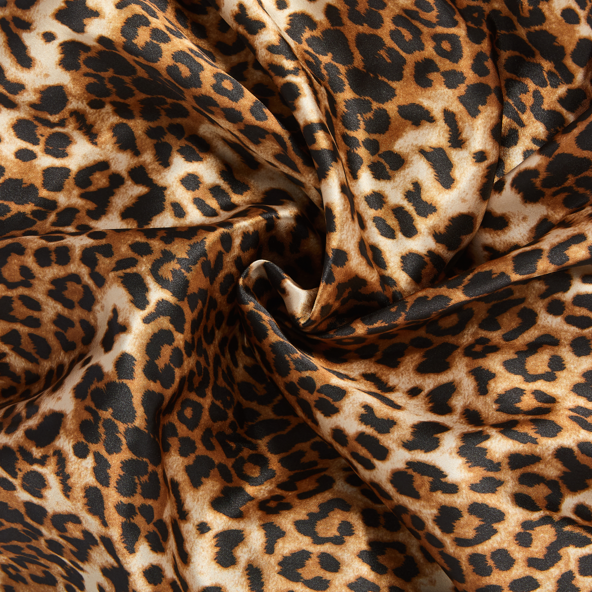 Leopard print silky satin fabric with smooth texture and a slight sheen, shown in a close-up twisted fold.