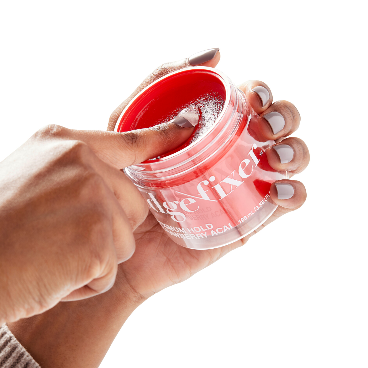 Hand with neutral-toned nails dipping finger into a bright red gel in a clear jar labeled \