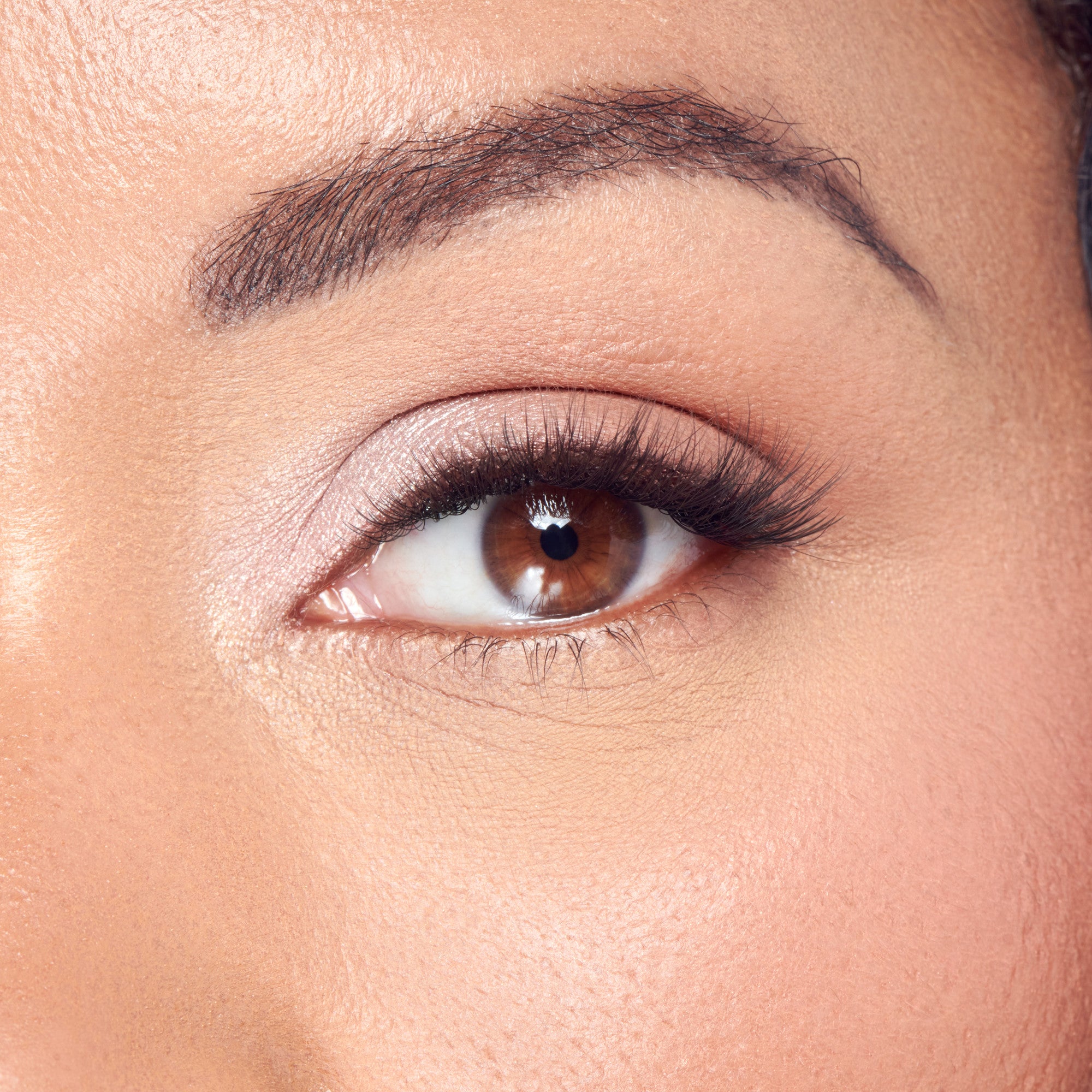 Close-up of eye with dark eyeshadow, winged eyeliner, and full lashes on fair skin.