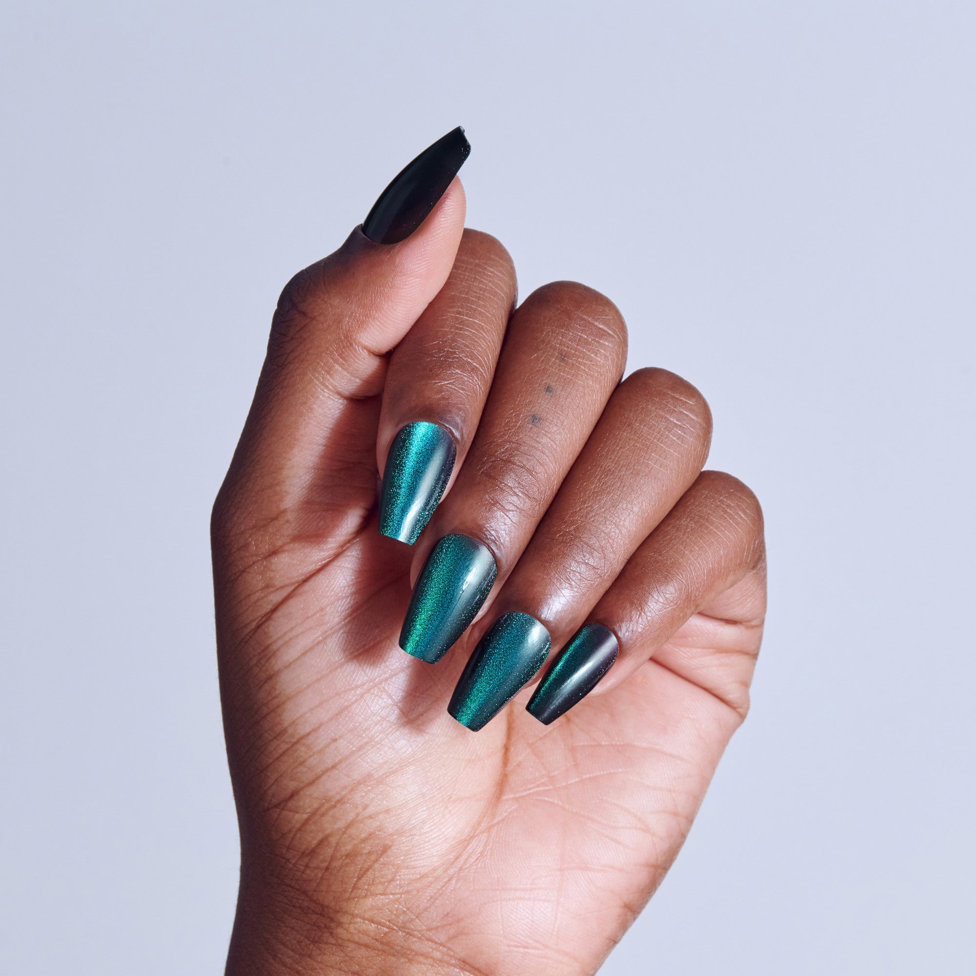 Hand displaying manicure with teal shimmer and black coffin nails against light background.