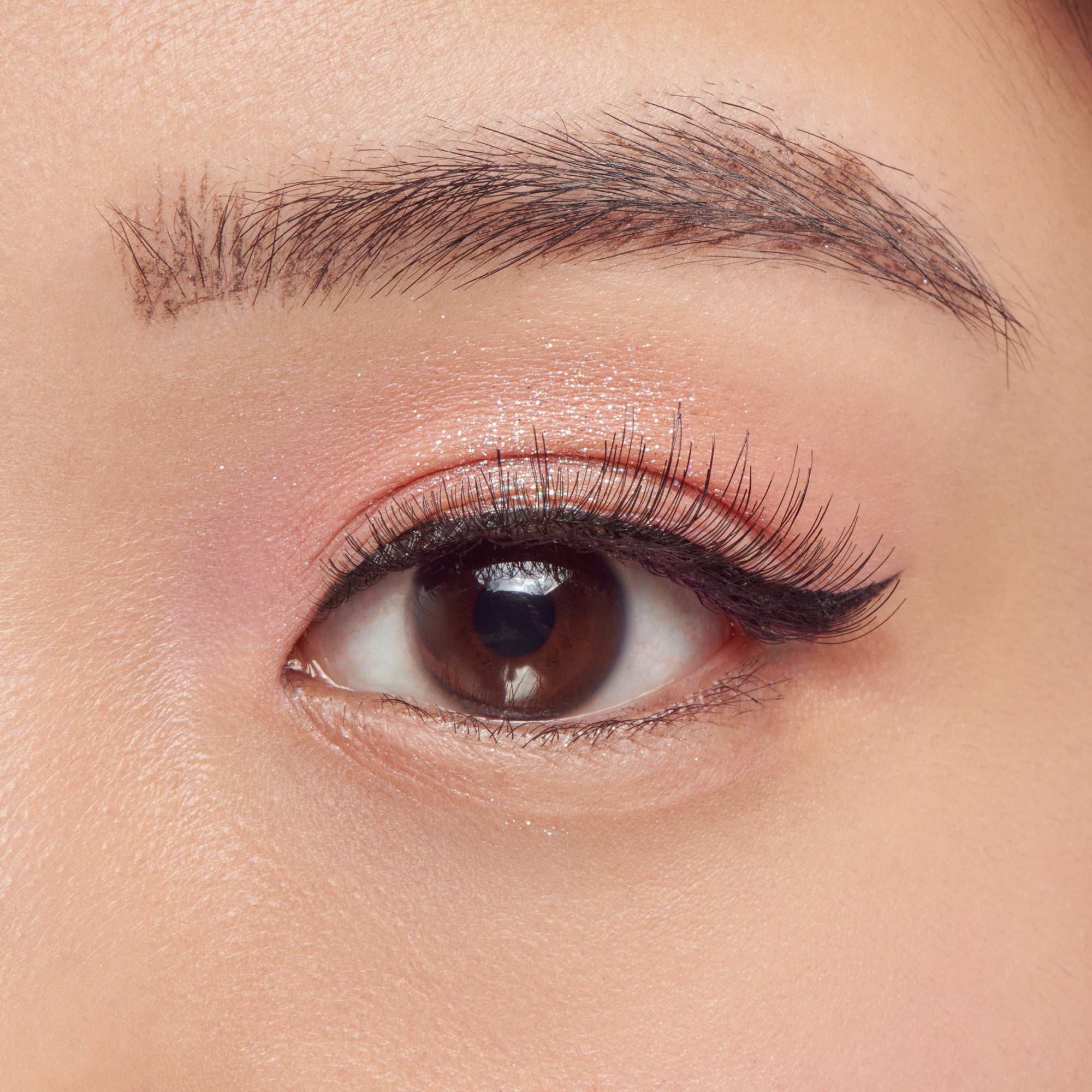 Close-up of a brown eye with makeup on a neutral background