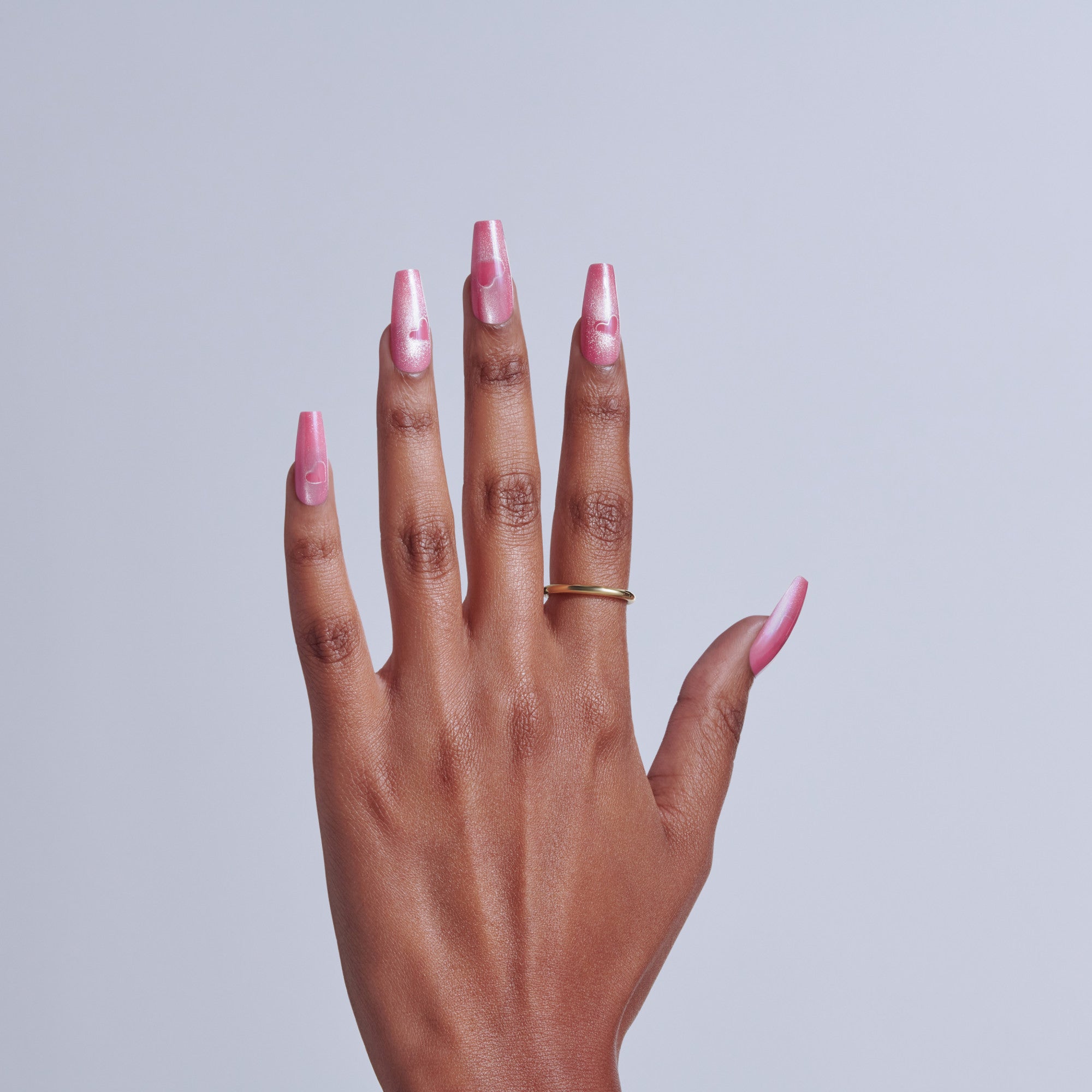 Hand with pink glitter nail polish on long acrylic nails against white background.