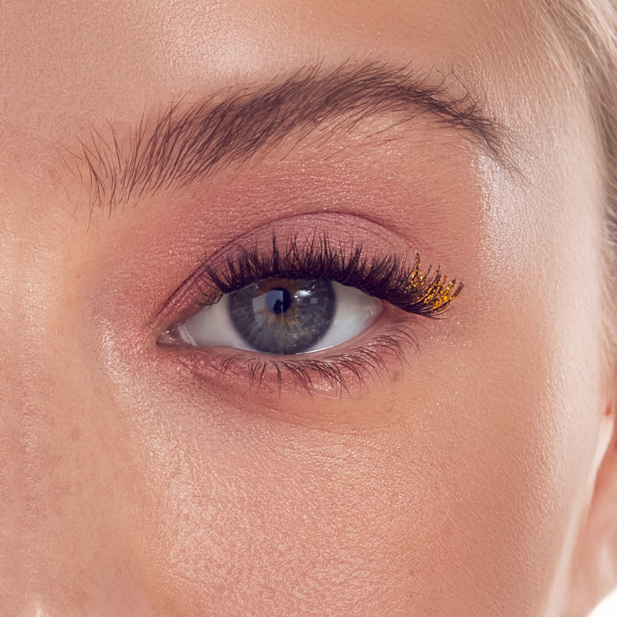 Close-up of eye with gold and burgundy eyeshadow and black mascara.