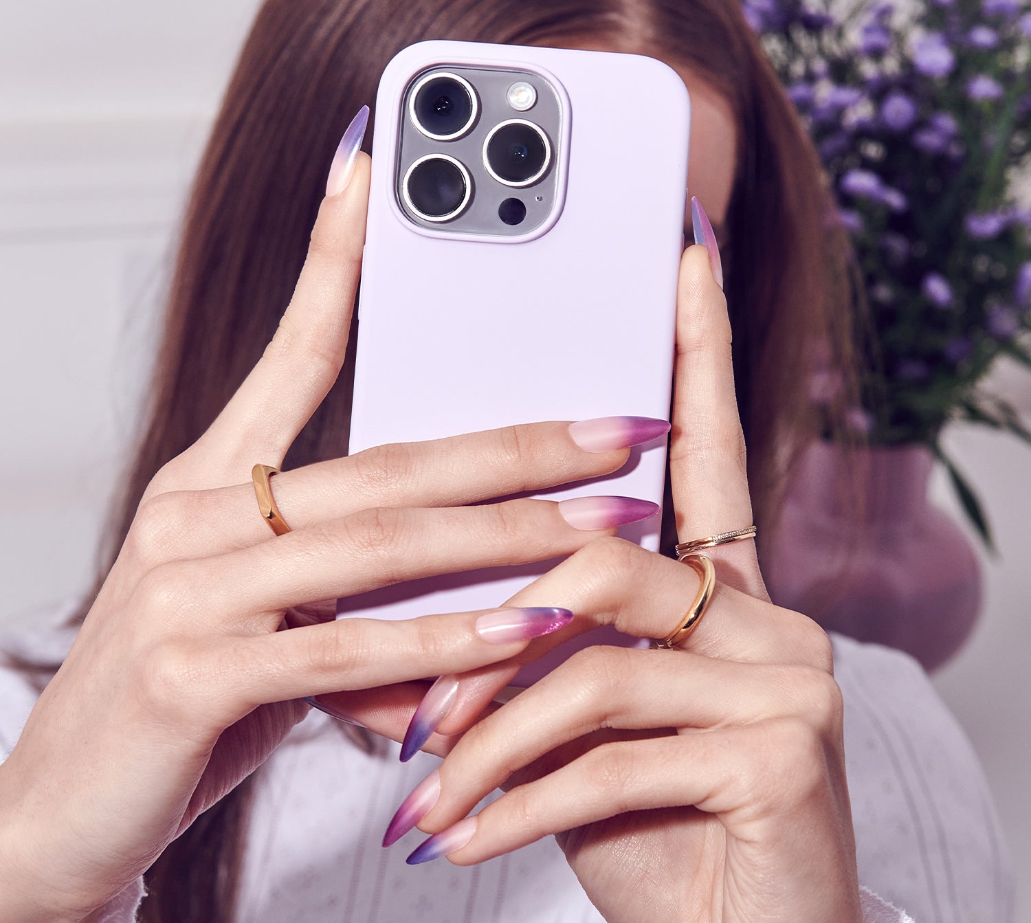 Person holding a phone with a blurred background of flowers