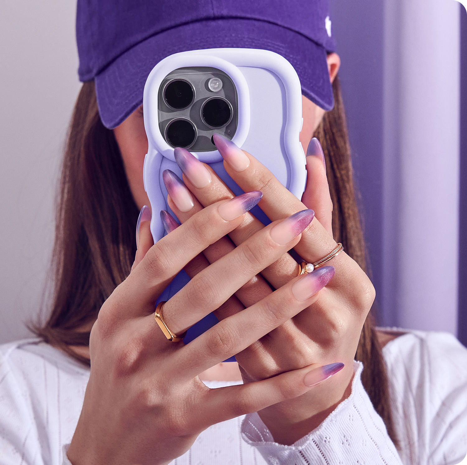 Woman holding lavender iPhone case with purple ombre gel nails and gold rings