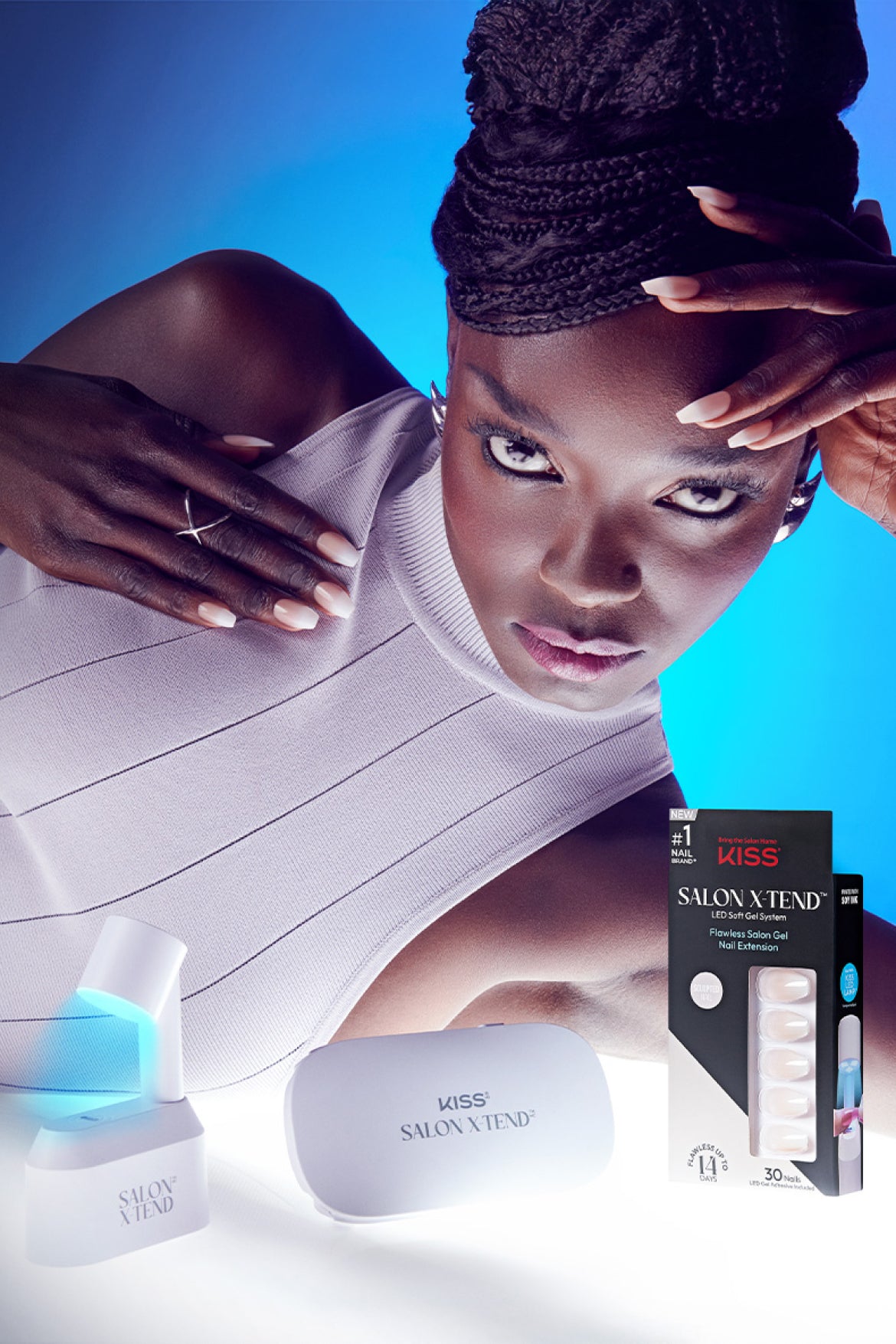 Woman displaying KISS Salon X Tend LED gel nail extensions with product packaging and UV lamp.