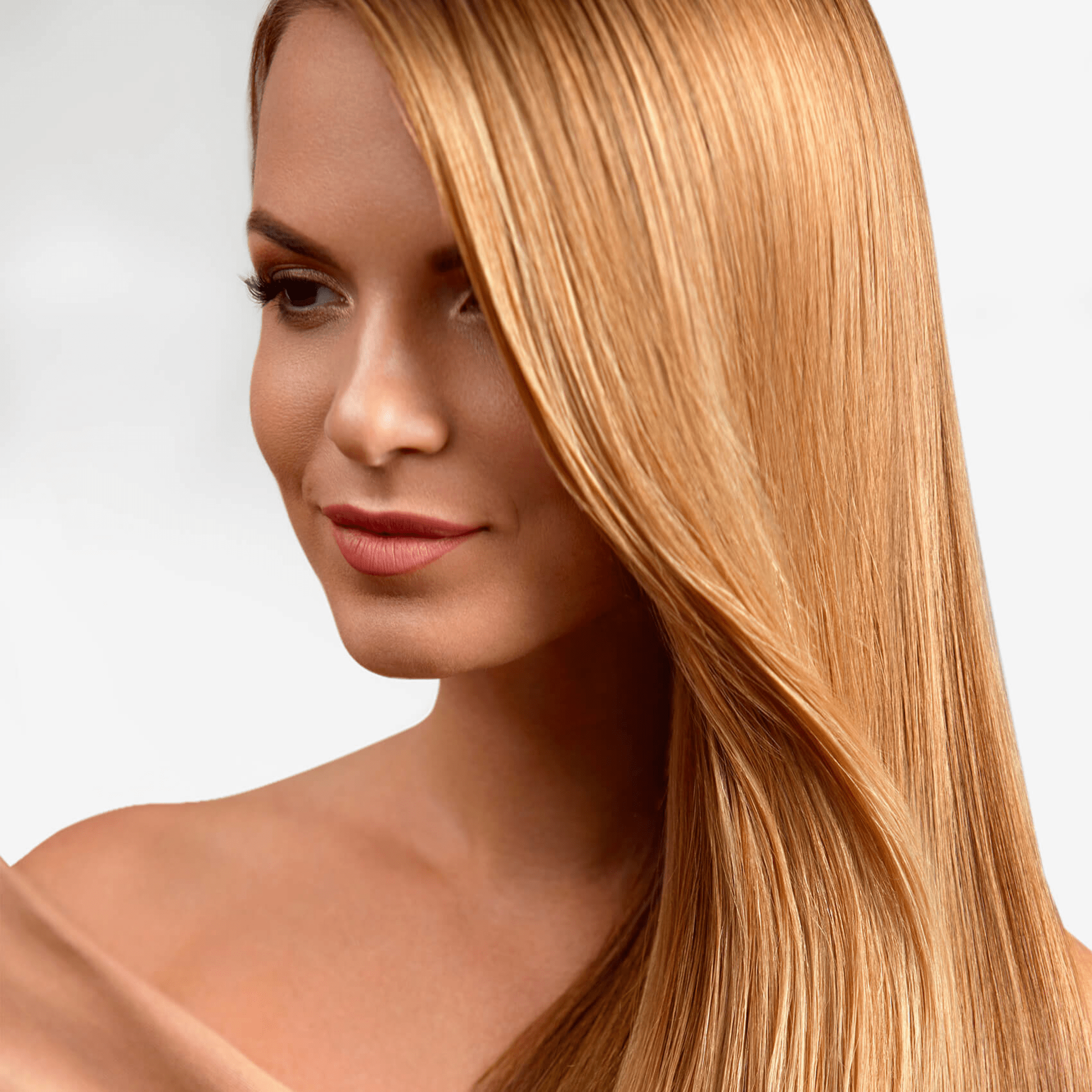 Woman with smooth, shiny, straight long blonde hair cascading over her shoulder against a neutral background.