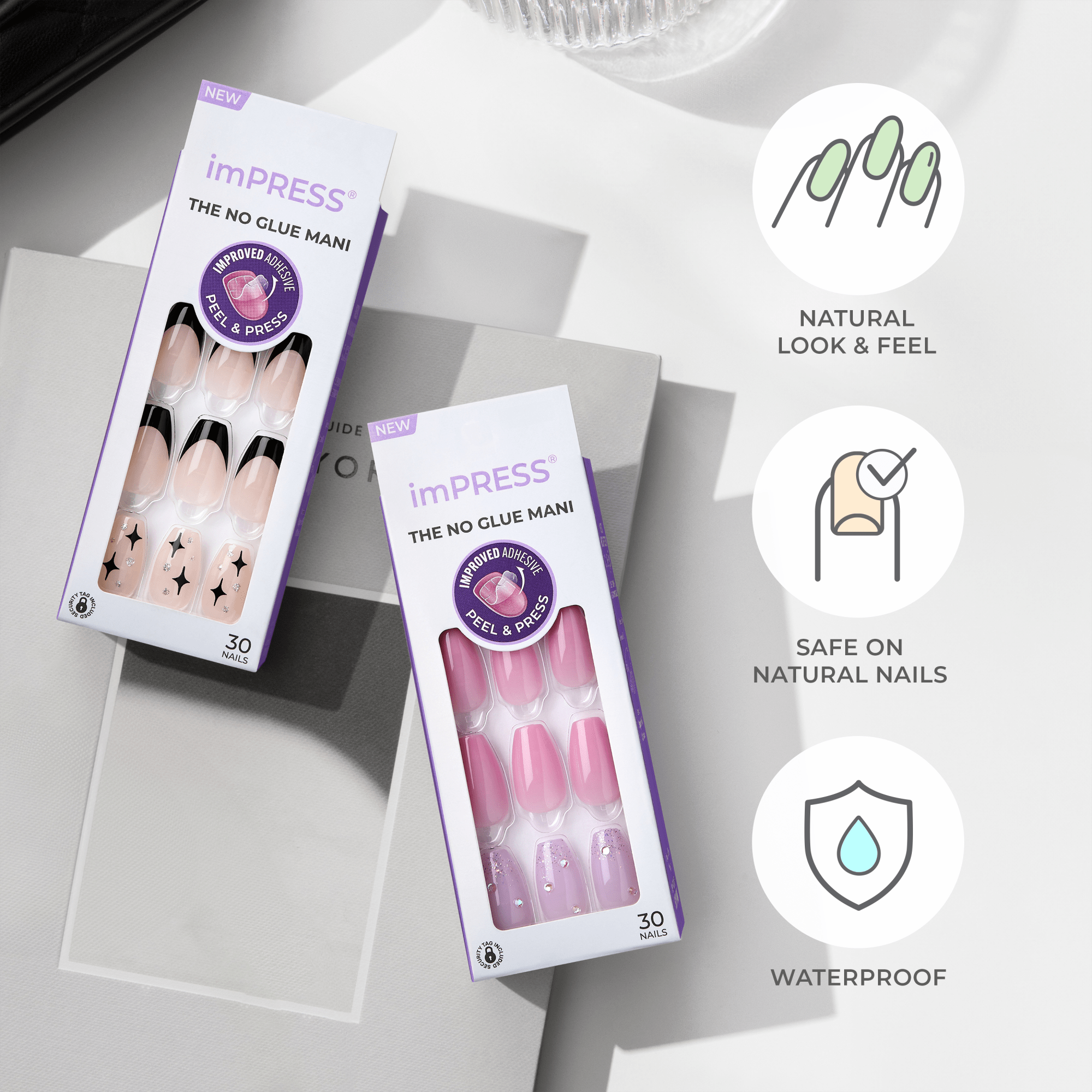 Two imPRESS Design Press On Nails packages displayed on a table with bright lighting. One package shows nude nails with black tips and star designs; the other shows pink nails with rhinestones and glitter.