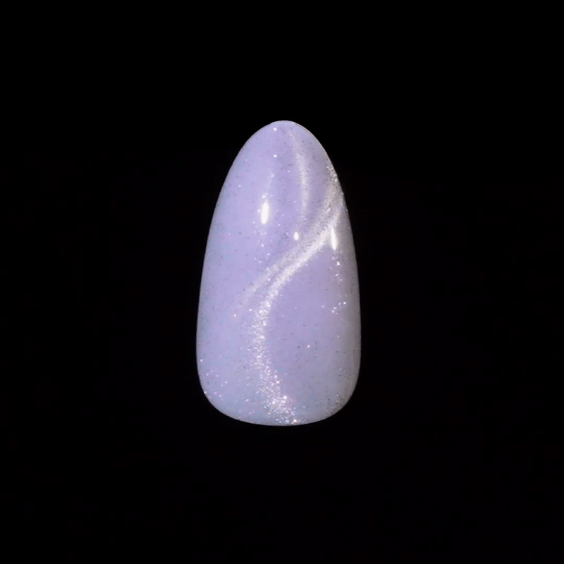 Single artificial nail tip with a glossy lavender base and a shimmering silver swirl glitter design, displayed against a black background.