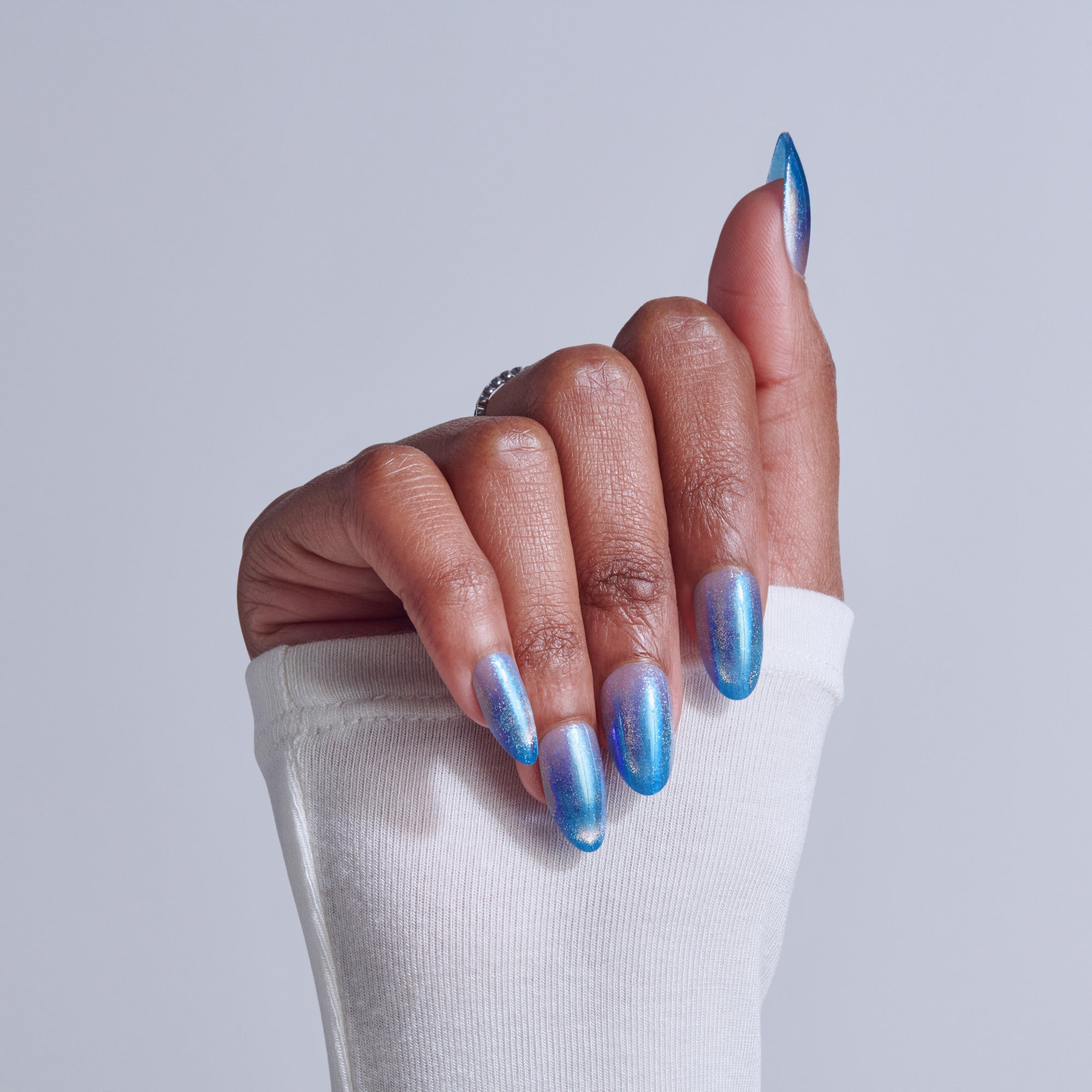 Blue chrome gel manicure with almond nails on white sleeve background.