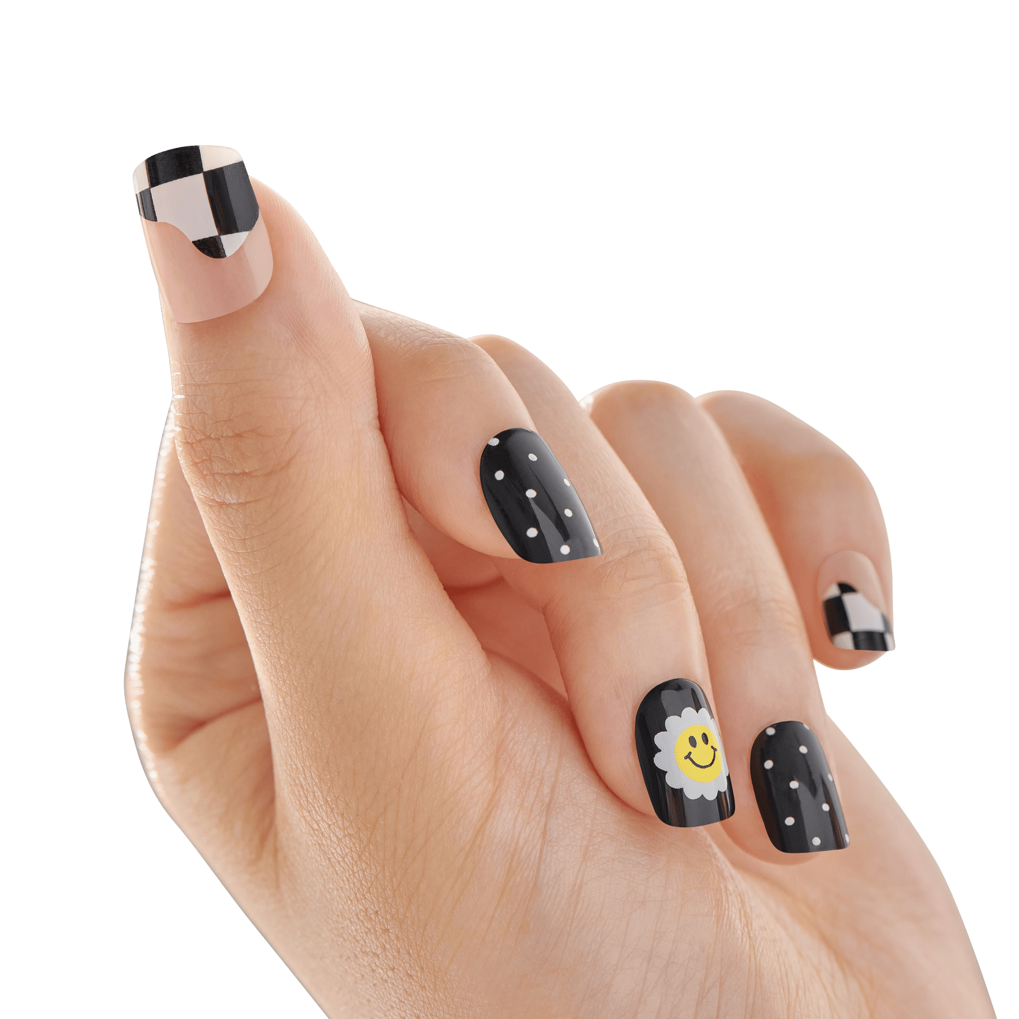 The image shows a close-up of a hand with manicured nails. The nails feature a variety of designs. The thumb and pinky nails have a black and white checkered pattern. The index and ring nails are painted black with small white polka dots. The middle nail is black with a white flower and a yellow smiling face in the center. The background is blurred, keeping the focus on the detailed nail art.