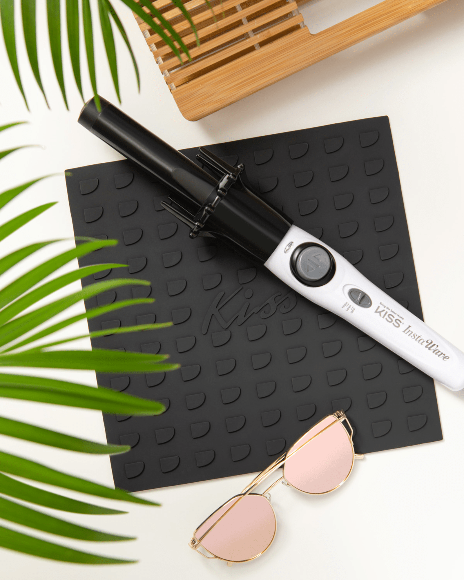 Black and white Instawave Automatic Hair Curler resting on a textured black mat with embossed \