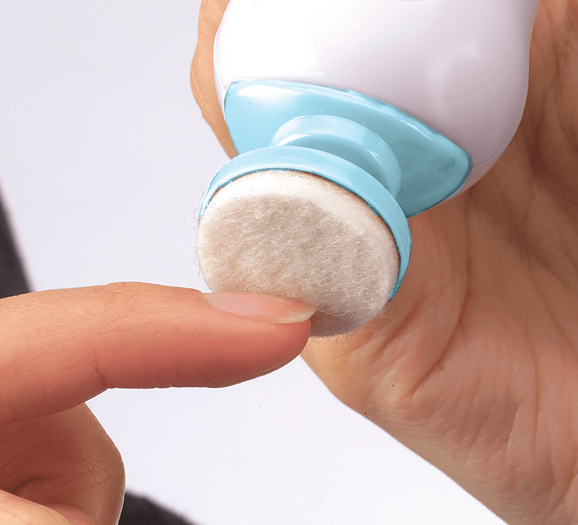 White and blue handheld electric nail file with a soft, round buffing tip, shown in use smoothing a fingernail on a light background.