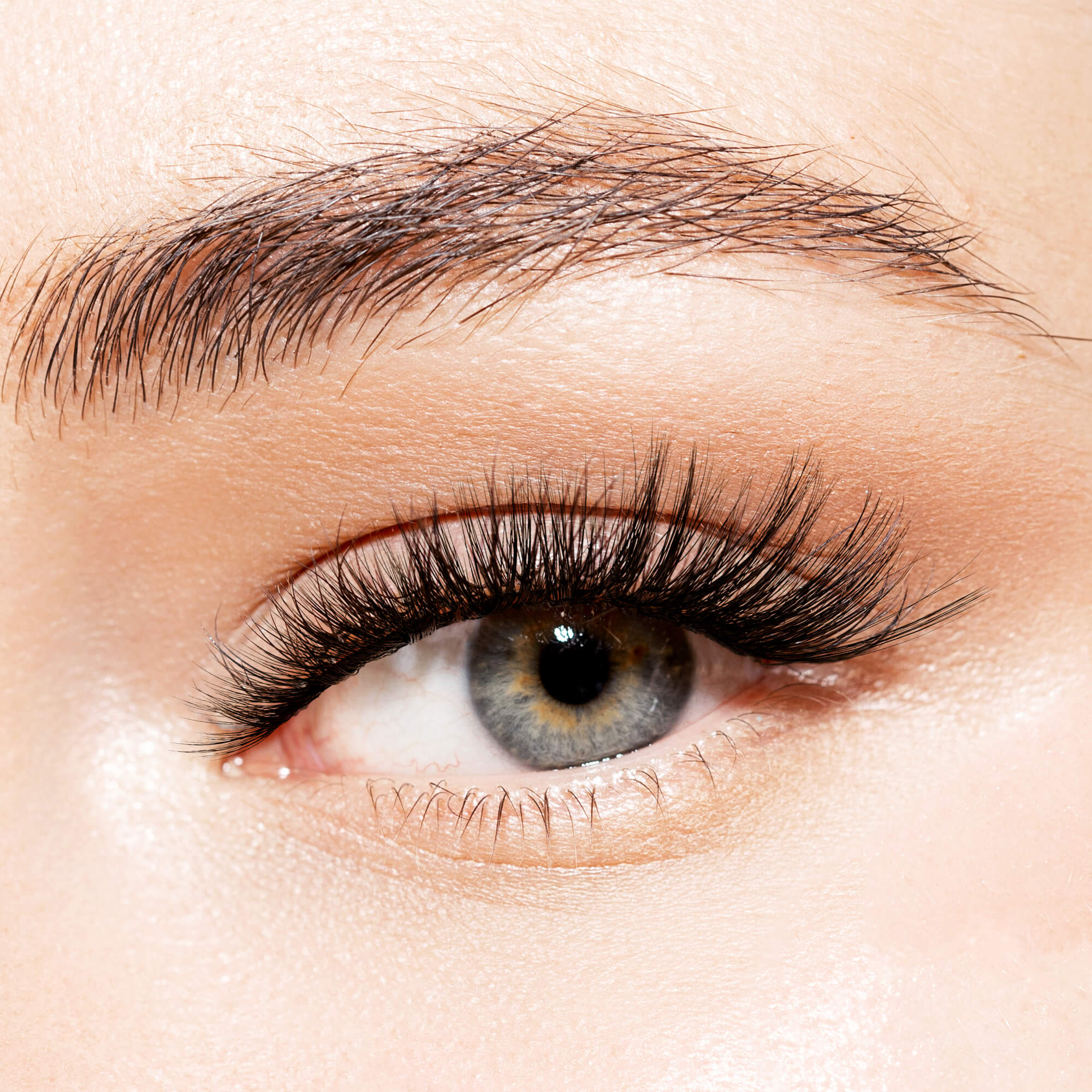 Close-up of a blue-gray eye with long, voluminous black false eyelashes applied, showcasing the KISS Lash Couture Triple Push-Up - Robe style.