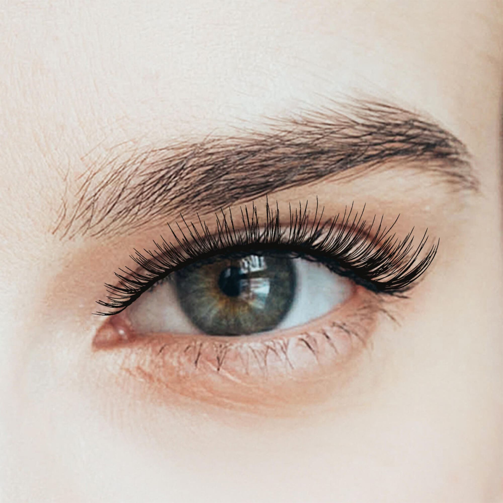 Close-up of a light-skinned eye with natural-looking, long, and wispy false eyelashes applied, enhancing the lashes&