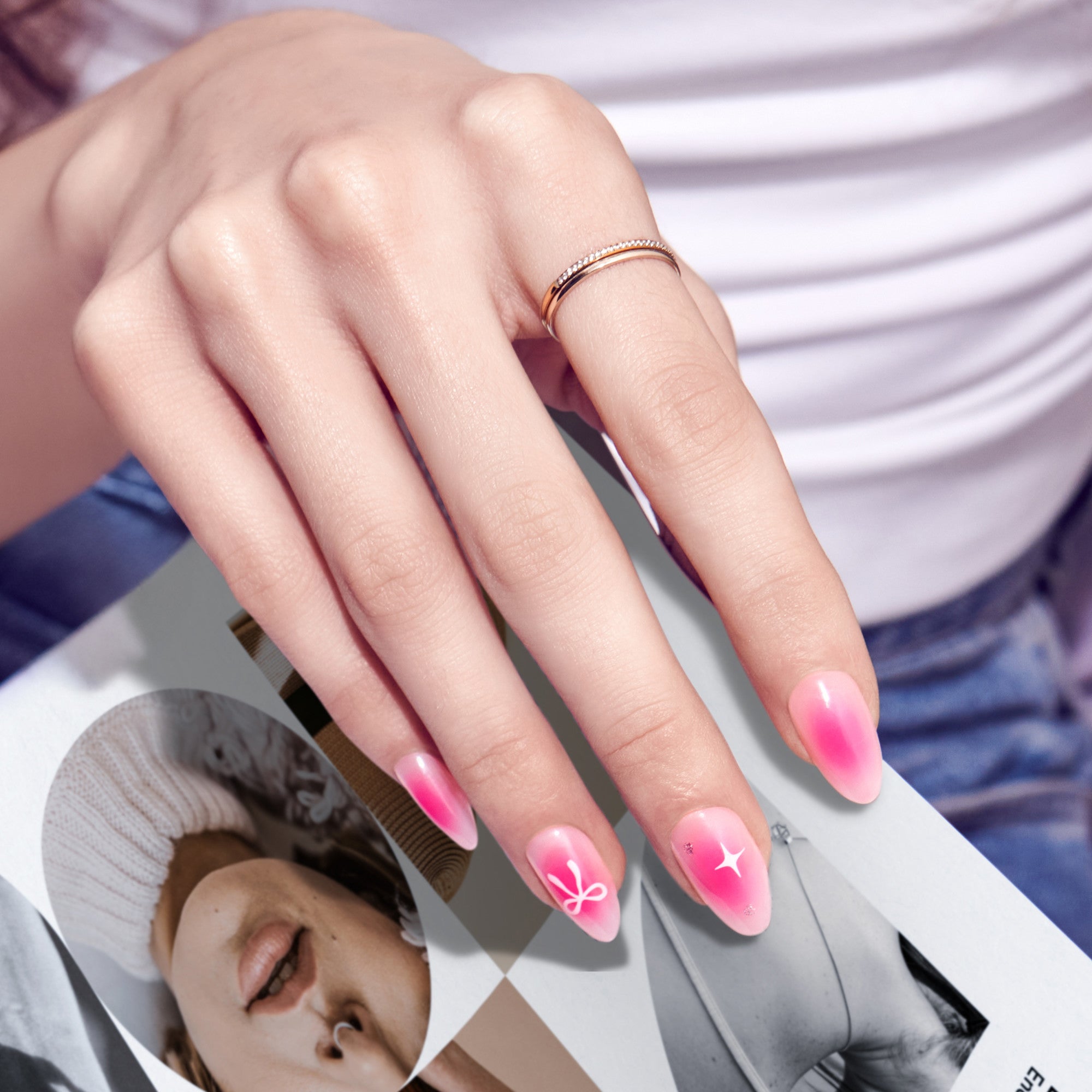 Almond nails with pink gradient and white star designs, rose gold ring visible.