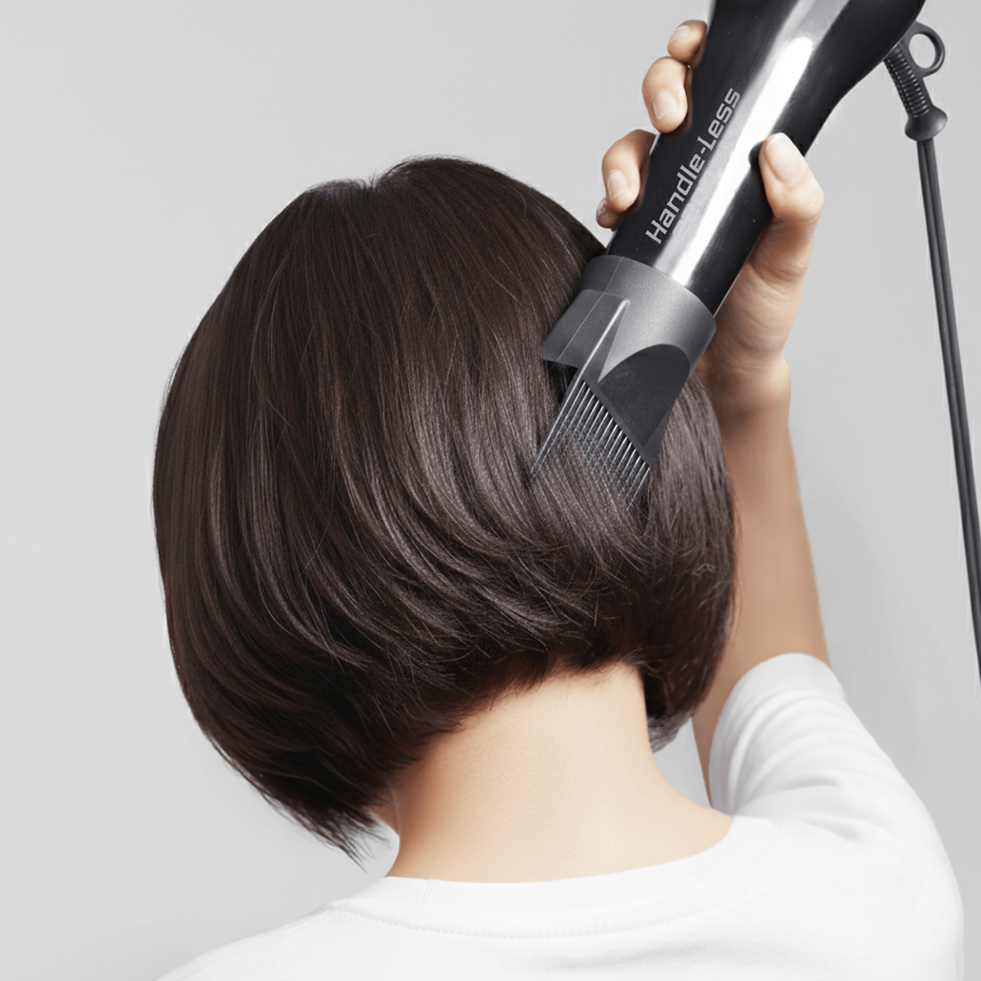 Back view of a person with short dark hair using a black Handle-Less 1875 ceramic tourmaline hair dryer with an attached comb attachment.