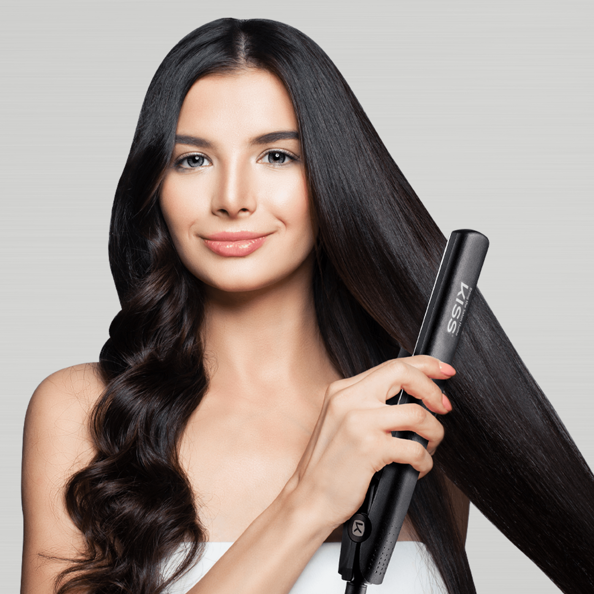 Woman holding a black KISS Nano Titanium flat iron styling one side of her glossy, long dark hair straight, while the other side remains wavy.