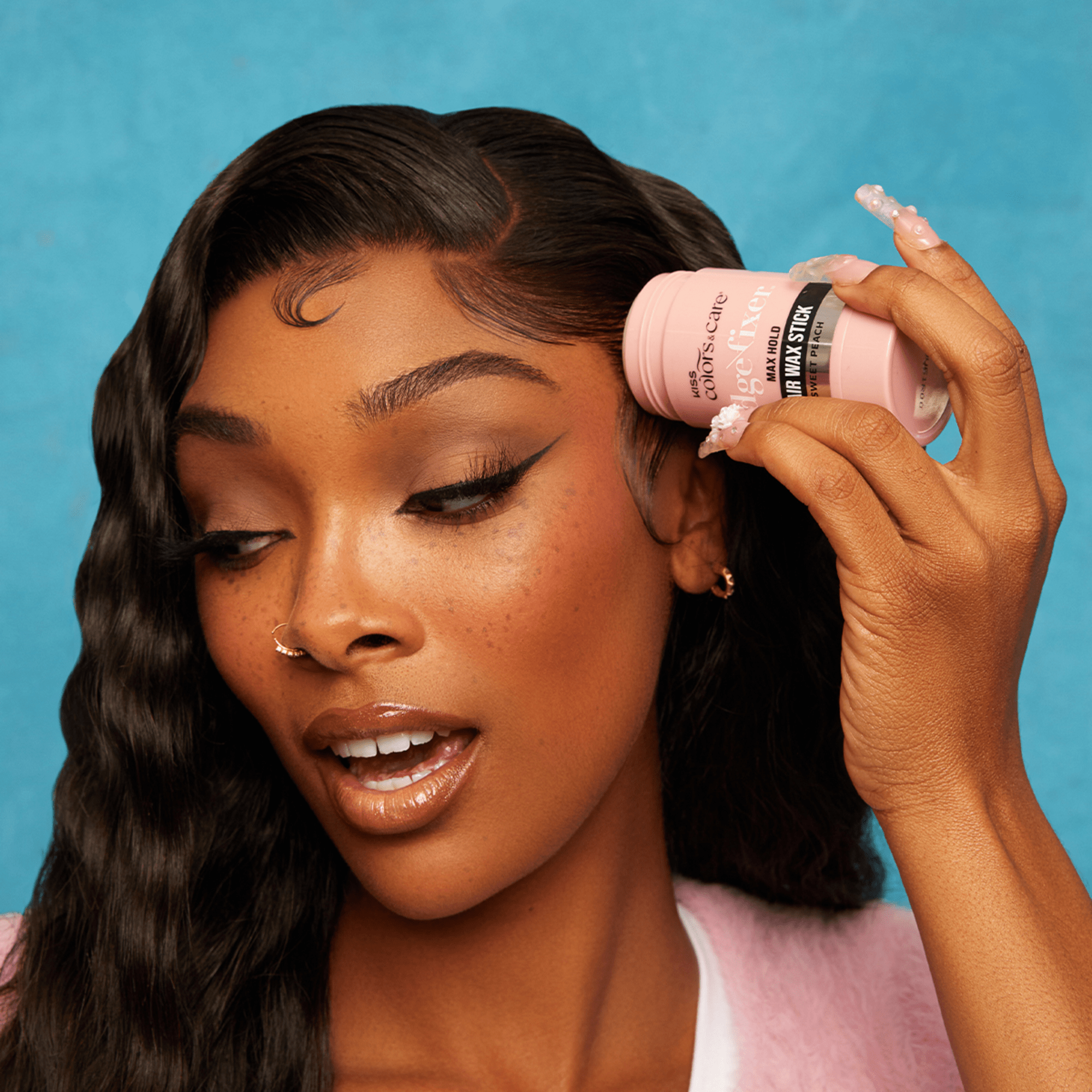Woman with sleek styled hair holding a pink Edge Fixer Wax Stick labeled "Max Hold" and "Sweet Peach" against a blue background.