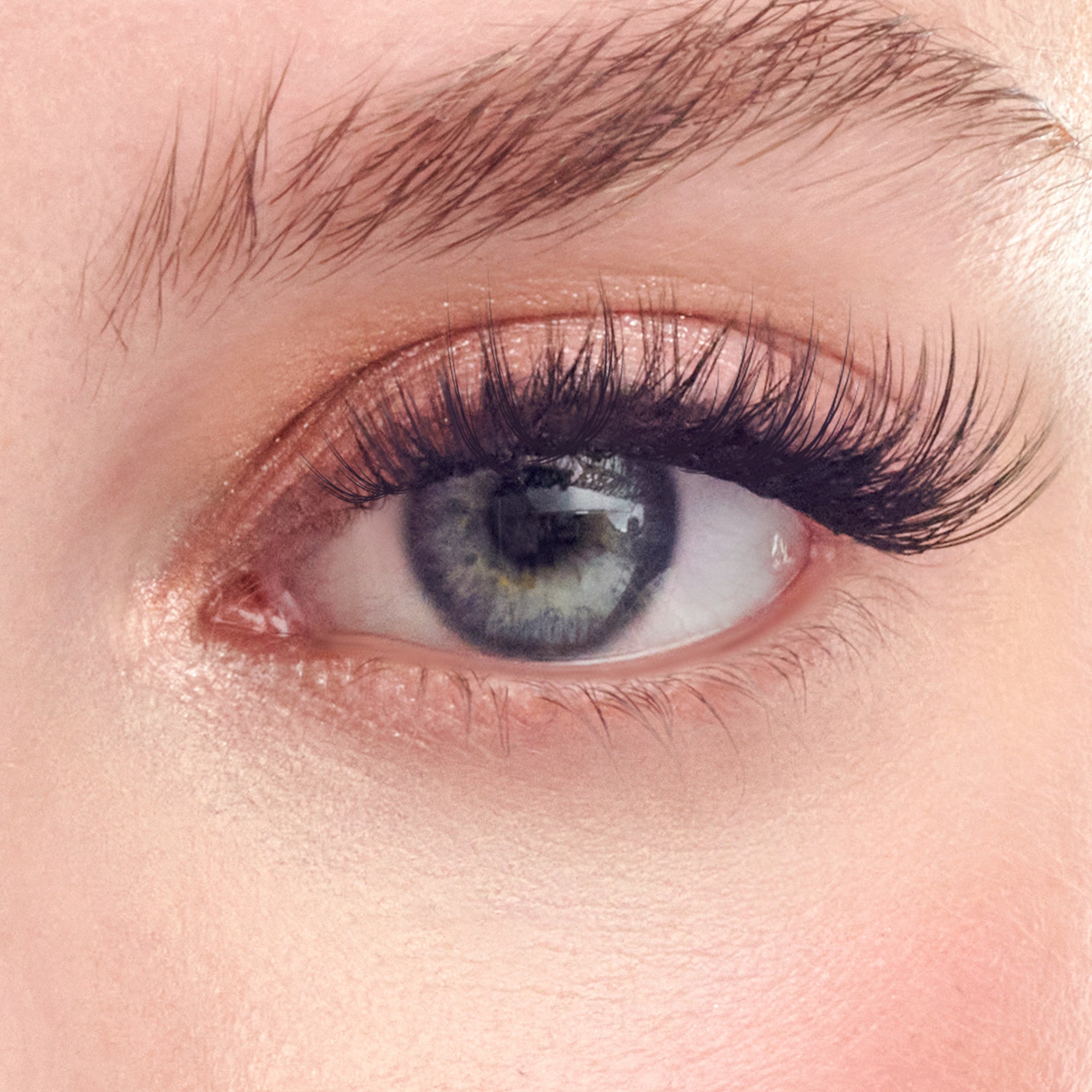 Close-up of a blue-gray eye with dark mascara and nude eyeshadow makeup.