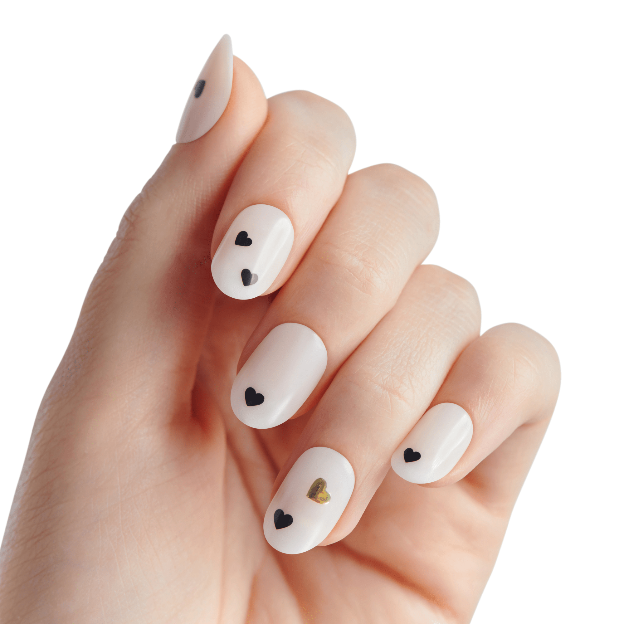 Hand with white press-on nails featuring small black heart designs on four nails and one gold heart on the ring finger, shown against a white background.