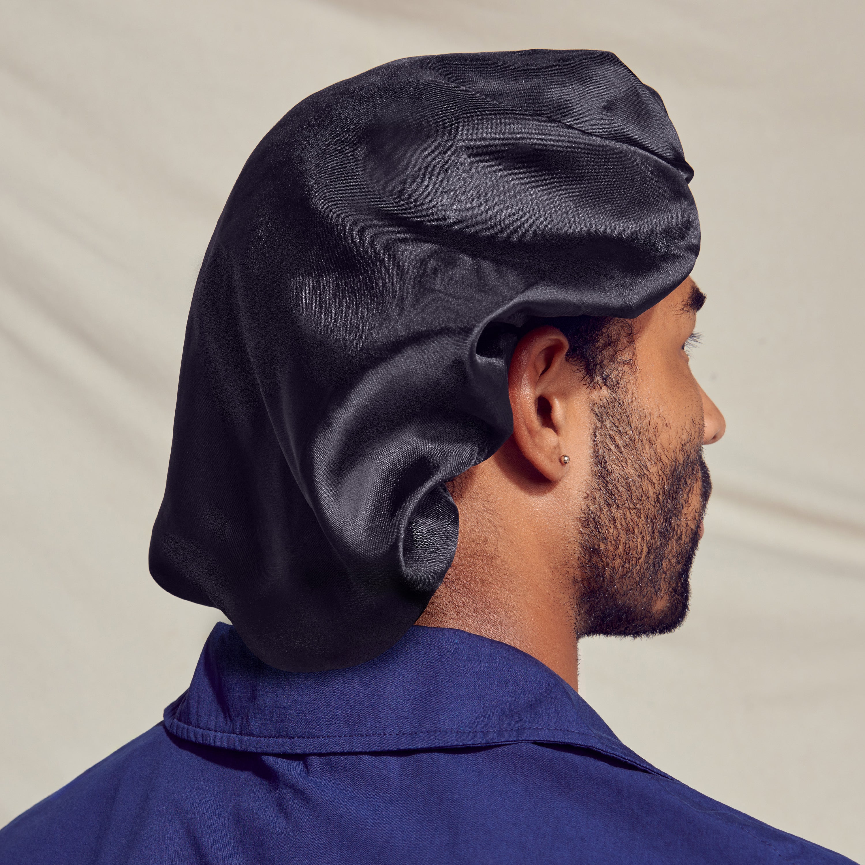 Black silky satin oversized bonnet worn on the back of a man&