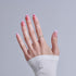 Hand displaying pink butterfly nail art with diamond ring on white sleeve background