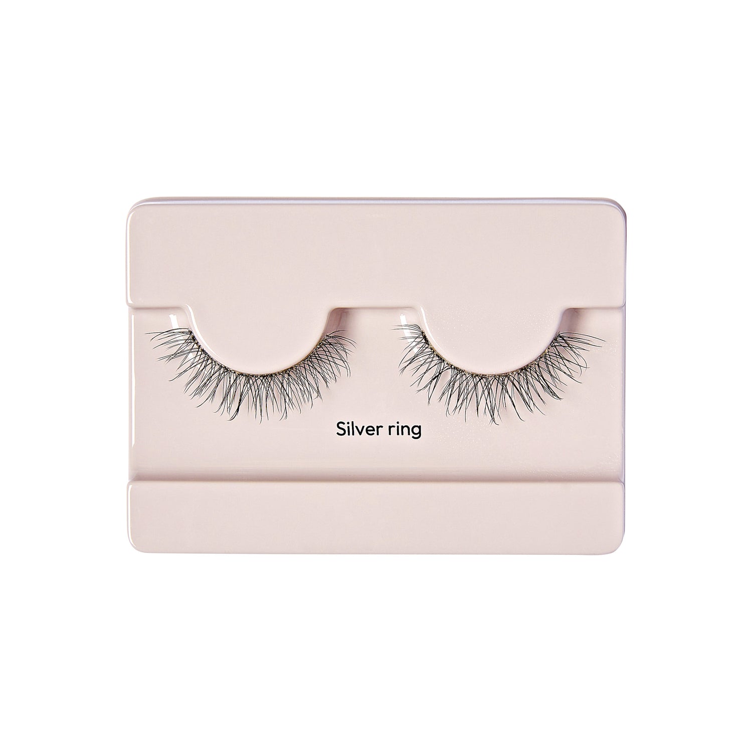 The image shows a pair of false eyelashes in a light pink plastic case. The eyelashes are labeled "Silver ring" and are neatly arranged in the case, which has a simple and clean design. The lashes appear to be long and voluminous, with a natural-looking curl. The case has a rectangular shape with a slightly raised section where the eyelashes are placed.