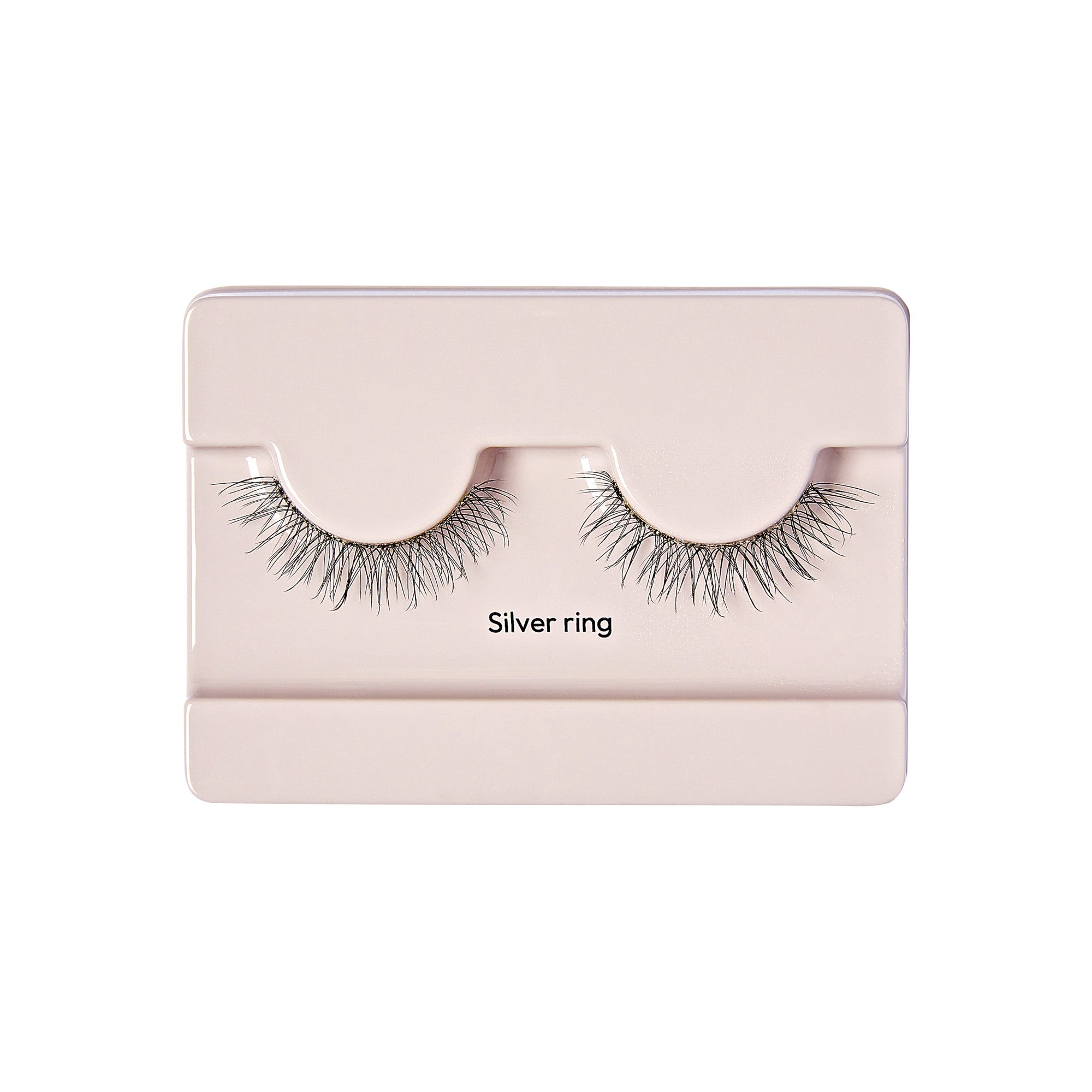 The image shows a pair of false eyelashes in a light pink plastic case. The eyelashes are labeled "Silver ring" and are neatly arranged in the case, which has a simple and clean design. The lashes appear to be long and voluminous, with a natural-looking curl. The case has a rectangular shape with a slightly raised section where the eyelashes are placed.