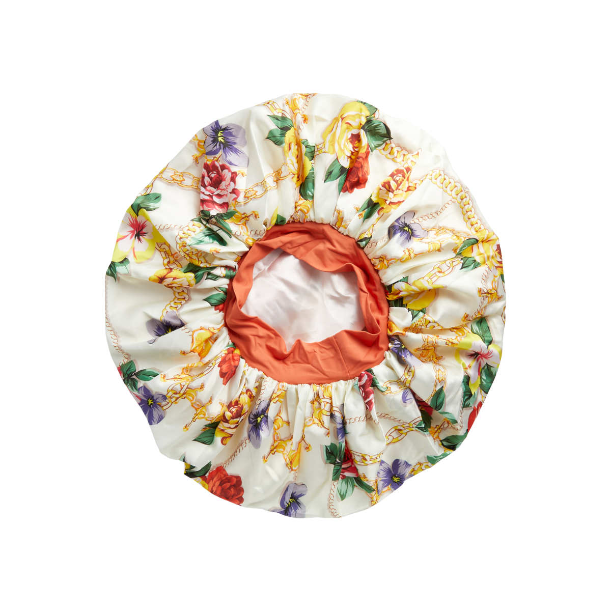 Super jumbo reversible hair bonnet with a cream base featuring a colorful floral and gold chain print, and a solid burnt orange interior lining.