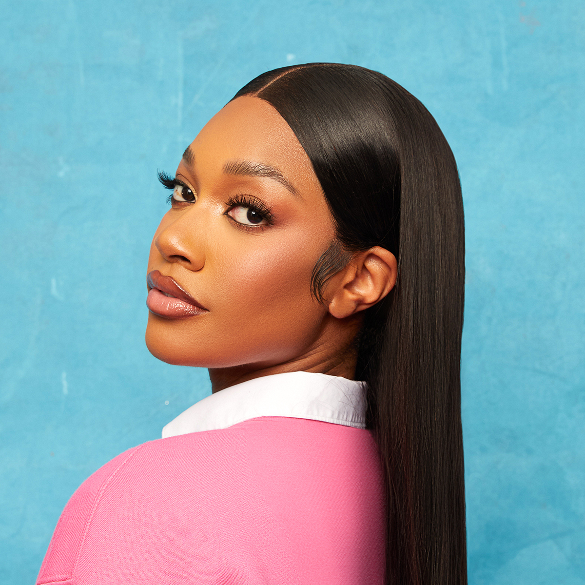 Young woman with long, sleek, straight black hair styled with a middle part, wearing a pink top with a white collar, against a blue background.