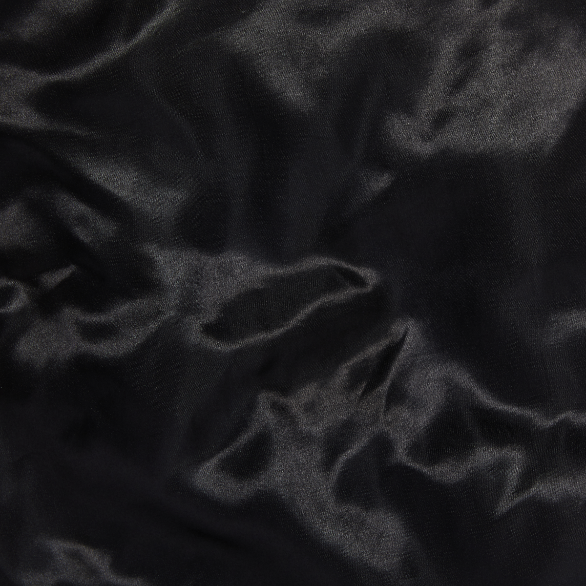 Black silky satin fabric with smooth, shiny texture and subtle light reflections, showcasing the material of a double wear cap.