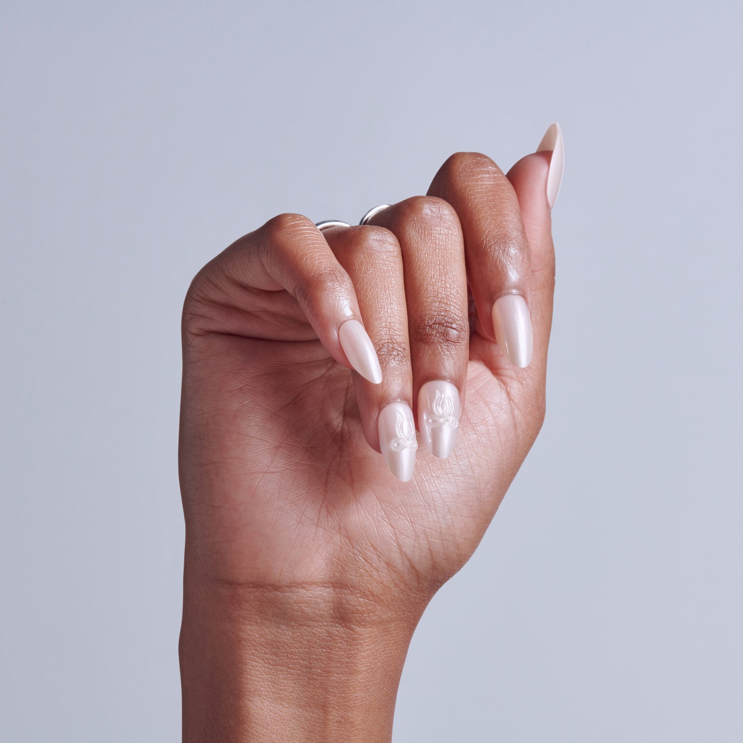 Hand displaying long almond-shaped nails with nude and white ombre nail polish design.