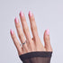 Hand with almond-shaped pink nails and silver ring, wearing black mesh sleeve.