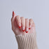 Hand with red and white ombre nail polish design, wearing beige sweater cuff.