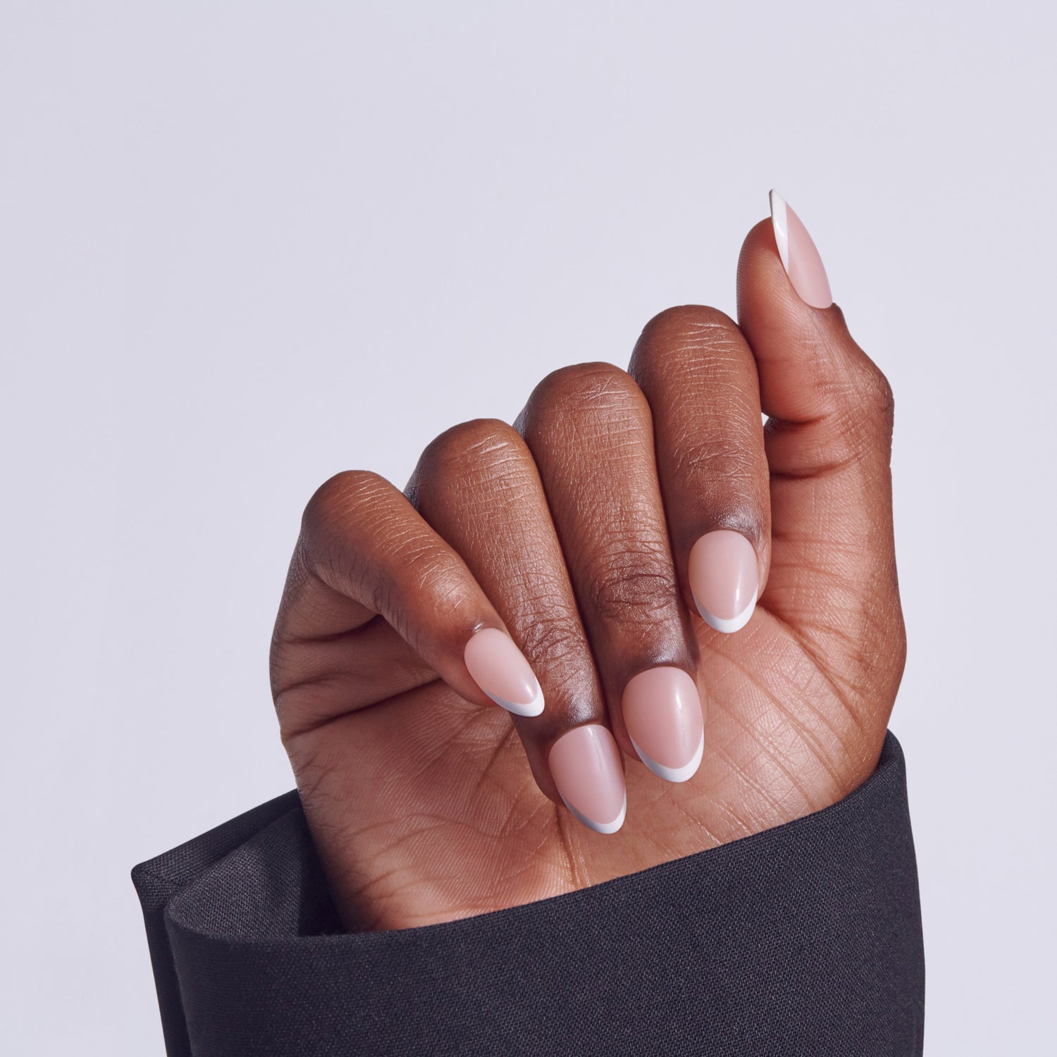 Hand displaying ombre nail polish with white tips and pink-nude base on almond nails.