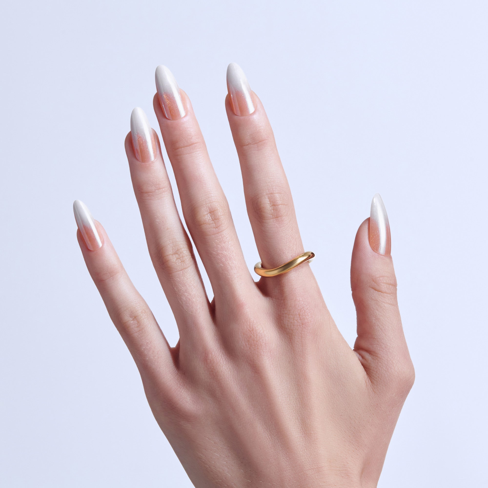 Hand displaying almond-shaped nails with white tips and nude base, wearing gold band ring.