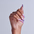 Hand with purple and pink gradient almond nails against white background.