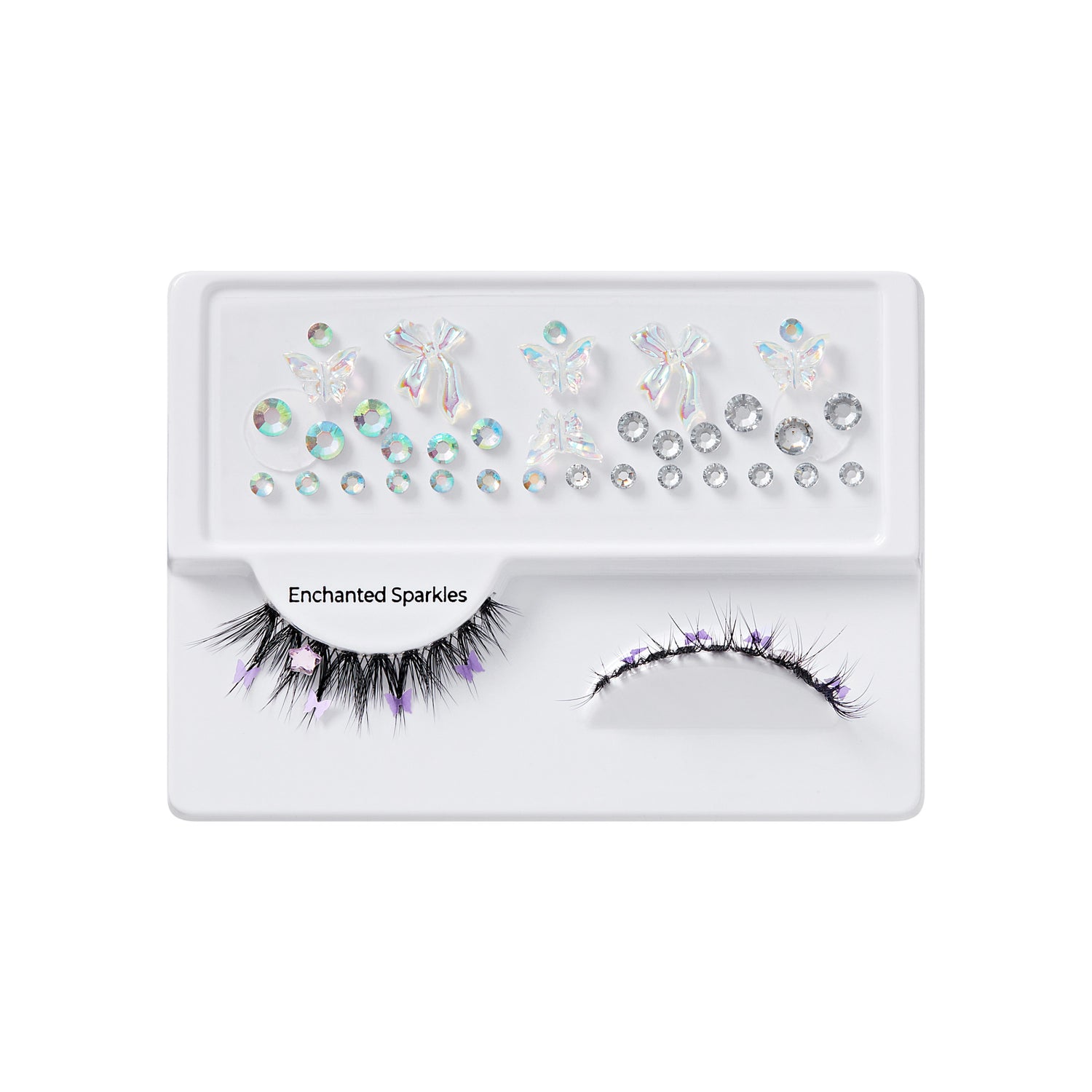 Black false eyelashes decorated with small purple butterfly and star accents, accompanied by iridescent gem stickers in various shapes on a white tray labeled \