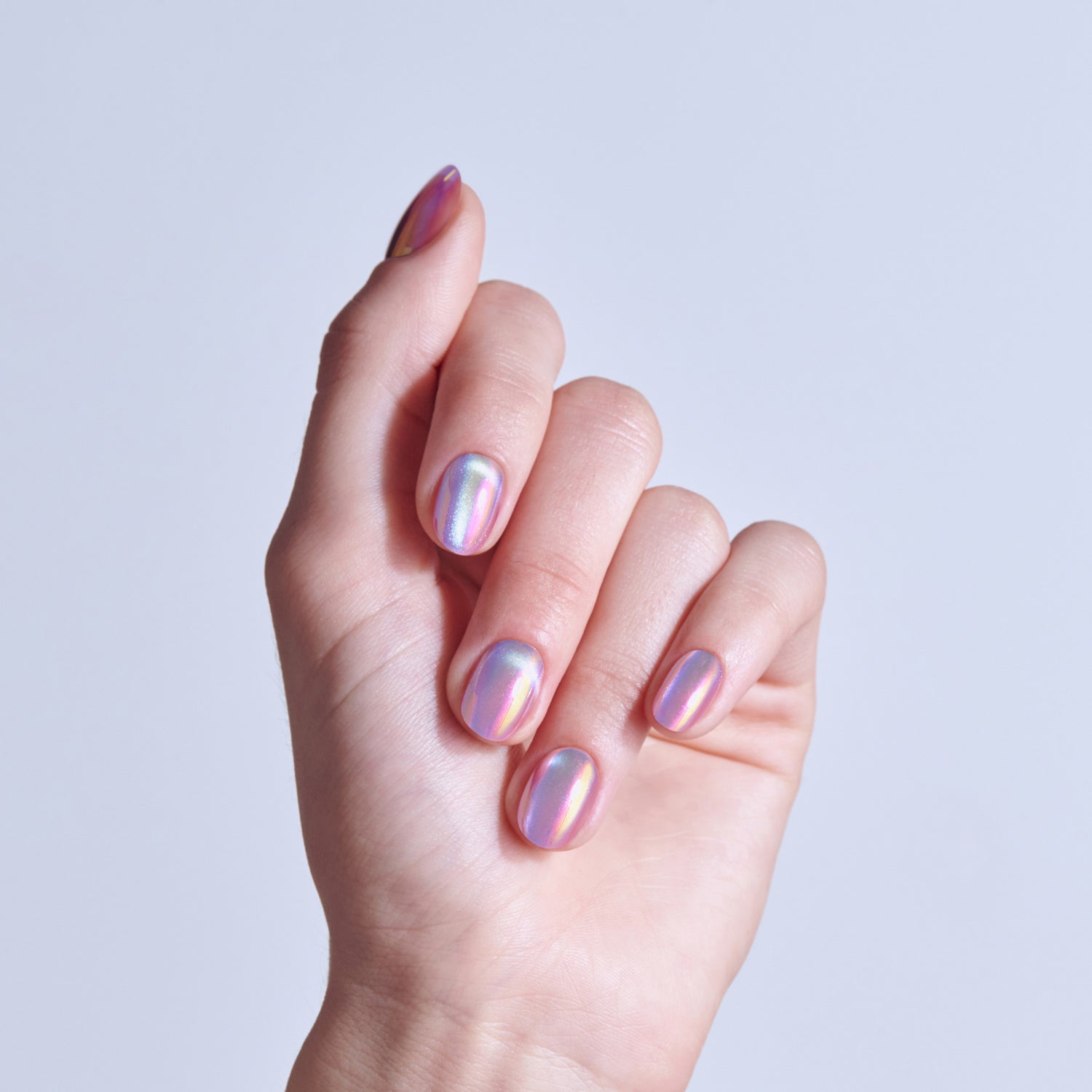 Hand displaying holographic iridescent nail polish in purple and pink tones.
