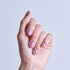 Hand displaying holographic iridescent nail polish in purple and pink tones.