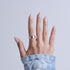 Hand displaying almond-shaped nails with white snowflake designs and pearl finish against light blue background.