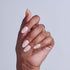 Hand with almond-shaped nails featuring white and pink ombre nail art design.