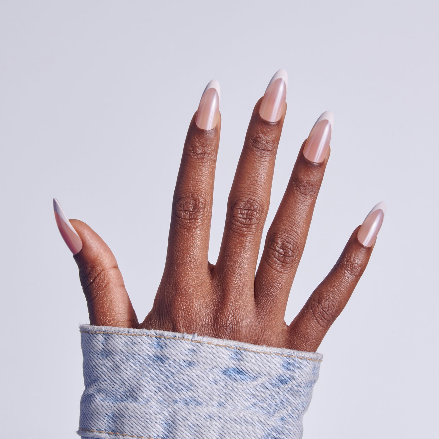 Hand with white French tip manicure against light blue fabric cuff
