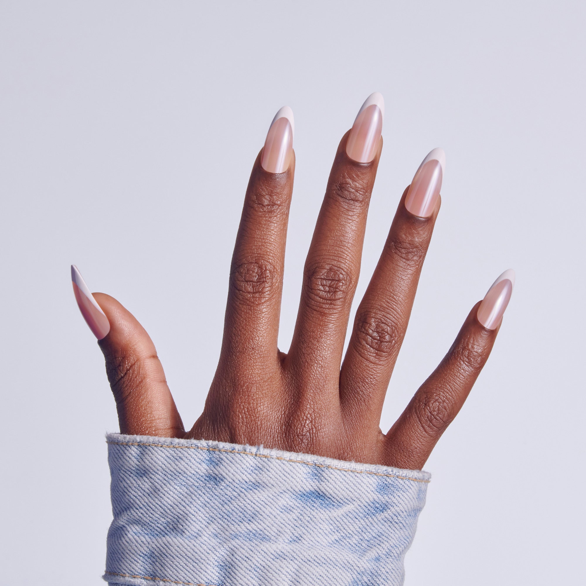Hand with white French tip manicure against light blue fabric cuff