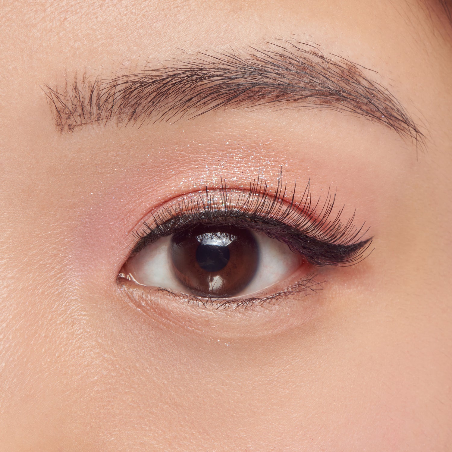 Close-up of a brown eye with makeup on a neutral background